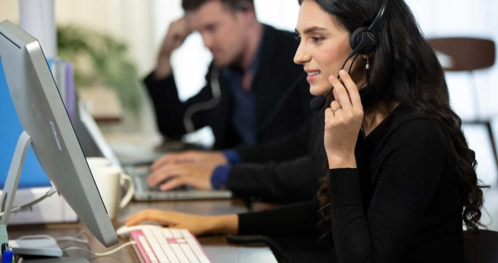 Medewerker met headset achter de computer aan de telefoon